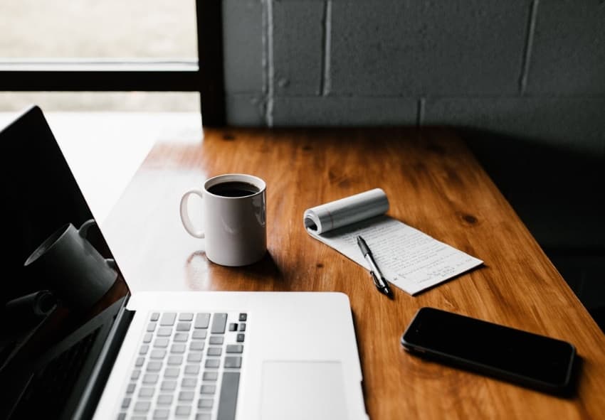 Desk with laptop, cup of coffee, and phone - Guerrilla usability testing