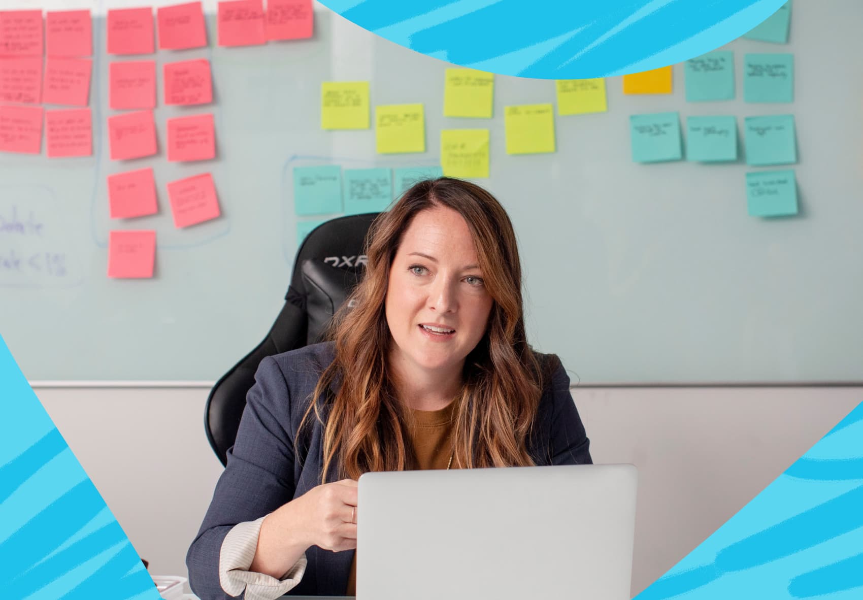 Woman sitting in front of a laptop with post-it notes on a board in the background